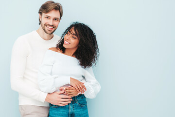 Smiling beautiful woman and her handsome boyfriend. Happy cheerful multiracial family having tender moments on grey background  in studio. Multiethnic models hugging. Embracing each other.Love concept