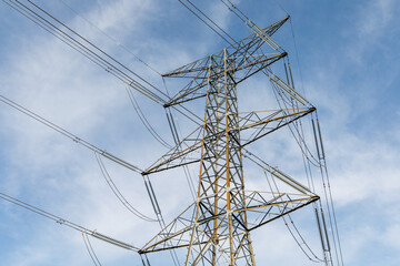 high part of high voltage power line tower with blue sky and some light clouds