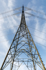 high voltage power line tower with blue sky and some light clouds view from below