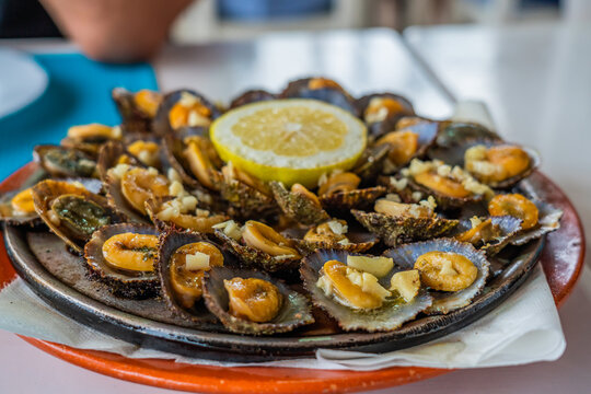 Seafood - grilled limpets served with lemon. Lapas grelhadas.