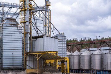 Granary elevator. Silver silos on agro-processing and manufacturing plant for processing drying cleaning and storage of agricultural products, flour, cereals and grain.