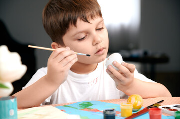 child looks at the Easter egg at the table. the child is preparing for Easter. selective focus 