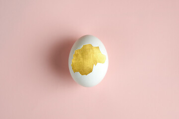 Golden Easter egg inside white egg. Pink background. preparation for Easter. place for text. selective focus 