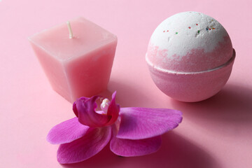 Obraz na płótnie Canvas Spa composition with Bubble Bath Bomb, candle and orchid flower on pink background. Pink salt bomb on pastel backdrop. Top view, copy space. Natural beauty spa body care product 