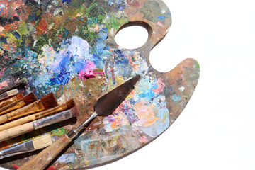 Artist palette with various colors oil paints and brushes on white background. Top view, copy...