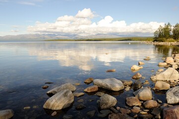 The peaks of the mountains, the Khibiny and a clear, bright sky with white clouds. View of the khibiny mountains from afar. Lake Imandra in summer. Kola Peninsula