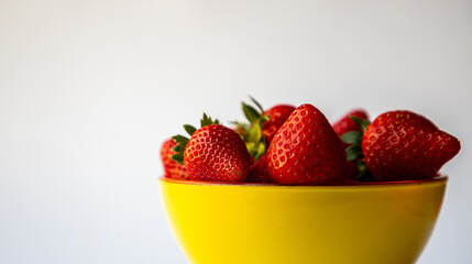 Red strawberries in a yellow bowl, white background