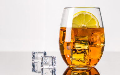 Glass of Alcohol Drink with lemon slice on white background. Whiskey or Brandy. Clear ice in cube shape. Frozen water. Ice maker. Fake or Artificial acrylic or plastic ice cubes.