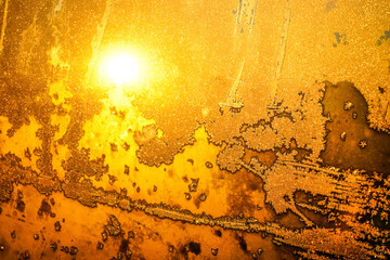 sunset sun shines through the frozen yellow window. Ice patterns on glass
