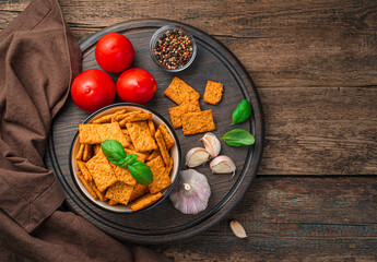Tomato crackers with basil and spices on a wooden background. Top view with copy space.