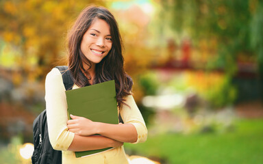 College student holding books walking on campus going to class smiling. Young smiling multiracial Asian woman girl with bag outdoor portrait. - Powered by Adobe