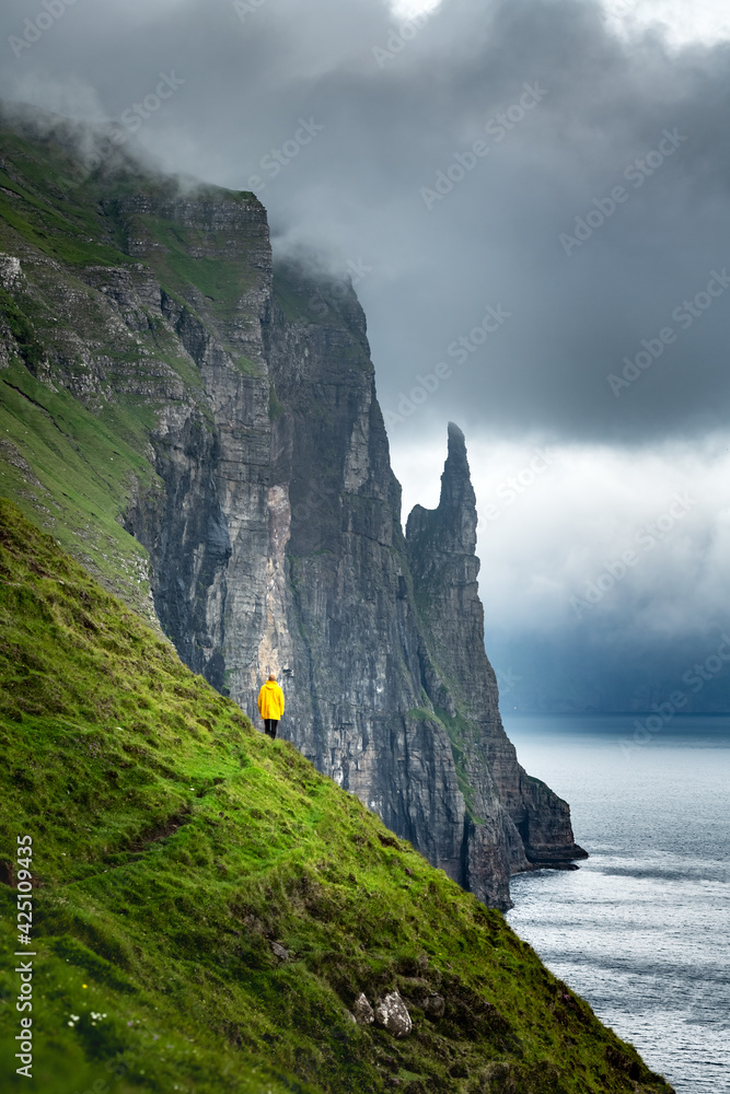 Wall mural Tourist with backpack in yellow jacket looks at Witches Finger cliffs