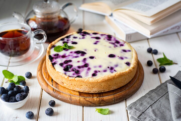 Sweet breakfast: delicious blueberry pie on a white table. Berry cake and a cup of tea