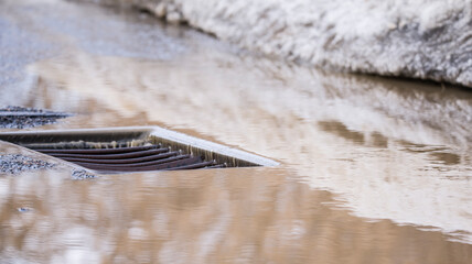 streams of water after the snow melts run along the road and merge into a storm drain