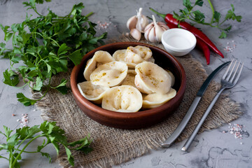 Vegan dumplings with pumpkin in a clay bowl on a gray background