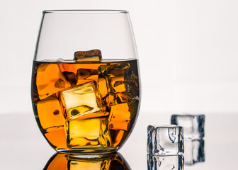 Glass of Alcohol Drink with Ice on white background. Whiskey or Brandy. Clear ice in cube shape. Frozen water. Ice maker. Fake or Artificial acrylic or plastic ice cubes.