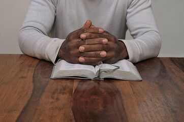 man praying with hand on bible on wooden table stock photo