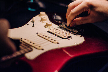 Maintetance, adjustment of red electric guitar with hands of a craftsman, luthier