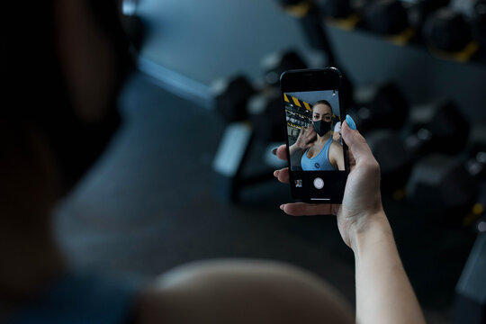 Girl in a black mask makes a selfie in the gym. the view from behind the shoulder.