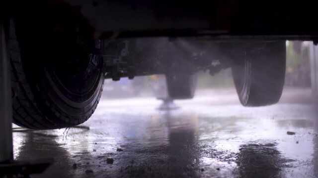 Image of man cleaning under a truck with a power washer at a repair shop.