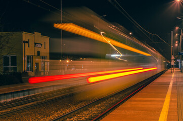 The lights of a running train at a train station.