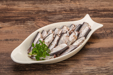 Anchovies in the bowl served basil leaves