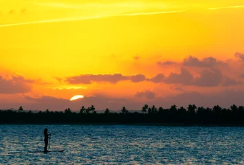 Foto op Aluminium Silhouet van een vrouw die tijdens zonsondergang een stand-up paddleboard peddelt op het strand van Serrambi. © Chico