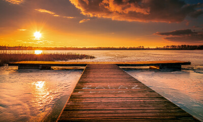 Fototapeta na wymiar beautiful, fabulous sunset over the frozen lake and the pier - Lake Rotcze