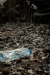 Fototapeta premium Ecology background. Plastic waste rubbish in forest, woodland. Garbage trash in environment. Empty used dirty bottles. Ecological problem.