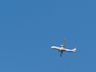  white propeller plane flies in the blue sky