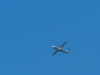  white propeller plane flies in the blue sky