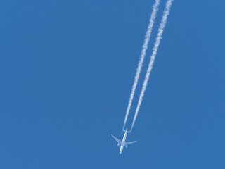  airplane flies in the blue sky and draws white vapor trails behind it