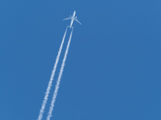  airplane flies in the blue sky and draws white vapor trails behind it
