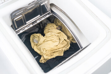Open washing machine with wet clothes after washing.