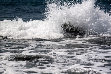 coast on a gray day, with waves and the sun reflecting off the stones