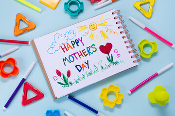 Mothers day card made by a child. Text Happy Mothers day. On a colored background, markers around and a constructor