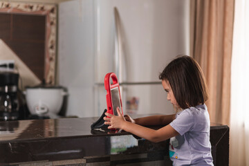 Niña sentada con una tableta dentro de  su casa 
