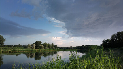 Shore of calm river at a cloudy day