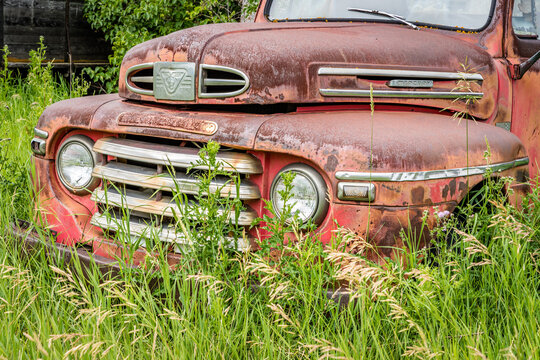 Weyburn, SK- July 19, 2020:  Classic red Mercury M series pickup truck abandoned in the tall grass on the Canadian prairies