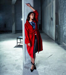 young pretty african american woman in luxury red coat posing fashionable on empty parking building, lifestyle rich people concept