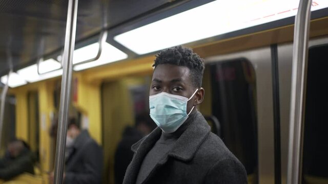 African man standing in subway metro wearing coronavirus mask underground