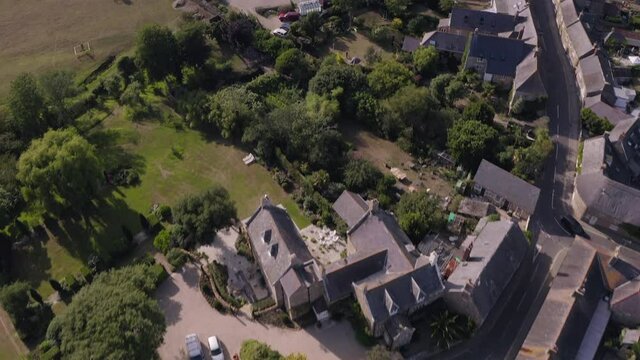 Aerial shot of traditional idyllic English village on a summer's day - starting from the church cemetery and tilting up towards the village - Abbotsbury, Dorset