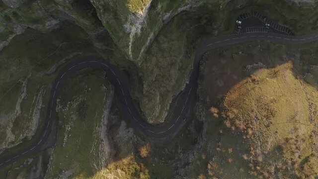 Overhead aerial tracking along empty bendy road winding through Cheddar Gorge, Somerset, UK