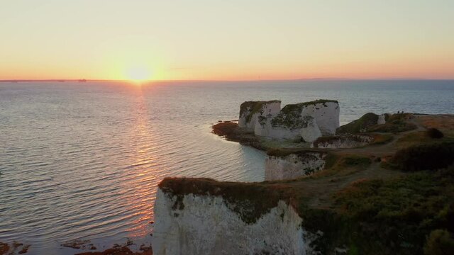 Aerial move towards the rising sun past the Old Harry rocks in Dorset, England's Jurassic coast 