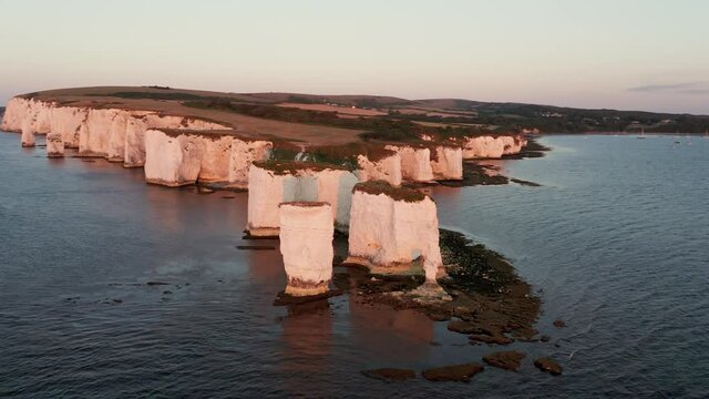 Aerial circling then pulling back from the Old Harry white chalk headland in Dorset, England's Jurassic coast at sunrise