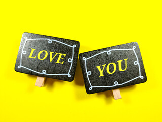 Selective focus.Wooden board with word LOVE YOU on yellow background.