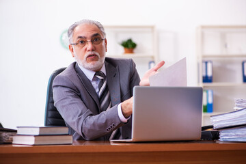 Old male businessman employee reading contract in the office