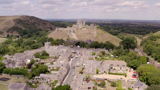 Wide aerial establishing move over the village towards Corfe Castle, Dorset, UK 