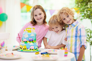 Fototapeta premium Kids birthday party. Child blowing out cake candle