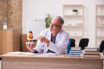 Old male doctor cardiologist sitting in the classroom